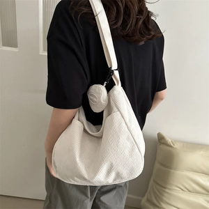 Minimalist beige corduroy crossbody bag with wide strap and round decorative pouch