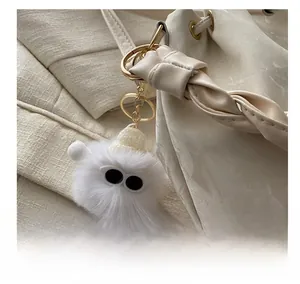 Gros plan d'un charme monstre blanc pelucheux avec de grands yeux sur un sac seau en cuir
