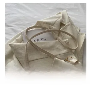 Détail de la fine bandoulière en cuir crème avec boucle en métal doré sur le sac seau