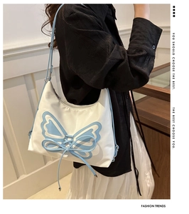 Detail showing white leather shoulder bag with light blue butterfly patches and ribbon ties