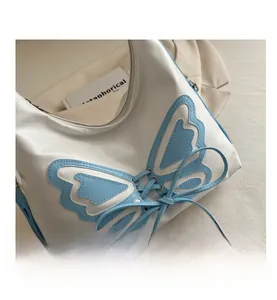 Détail du sac blanc avec motif papillon bleu en patchwork et décoration de nœud lacet
