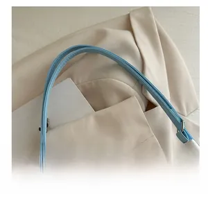 Gros plan de la poignée du sac bleu clair avec coutures précises et boucle métallique
