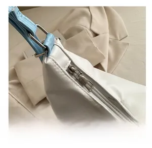 Détail du sac à bandoulière en cuir blanc avec sangle bleue et fermeture éclair argentée