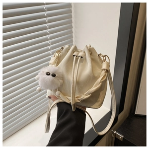 Sac seau beige à cordon avec pendentif en peluche blanche et bandoulière en cuir souple