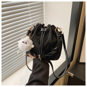 Détail du sac seau noir en cuir avec poignée tressée et charm monstre en peluche doux