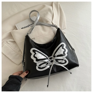 Close-up of black leather bag with silver butterfly patch and punk ribbon detail
