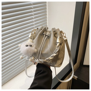 Gros plan du sac seau argenté marbré avec cordon et charm monstre en peluche blanc