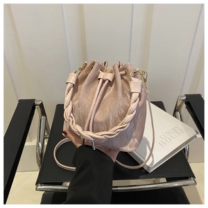 Détail du sac seau rose avec une poignée tressée et un design à texture plissée