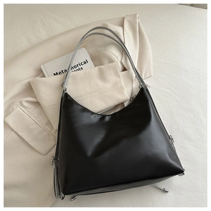 Detail of smooth black PU leather tote bag with silver hardware on neutral background