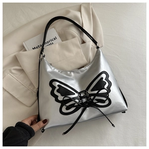 Detail of silver Y2K hobo bag featuring a black butterfly patch and lace-up design