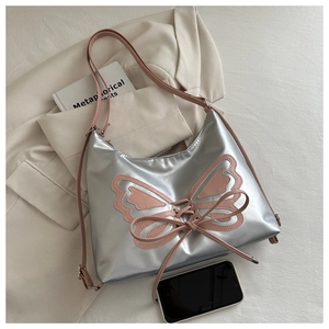 Detail of silver metallic shoulder bag with pink butterfly cutout on a white suit