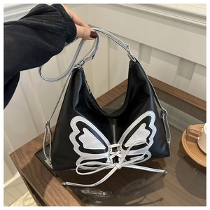 Detail of black PU leather moon bag featuring silver butterfly and lace-up accents
