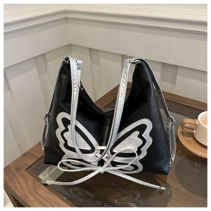 Close-up of black Y2K shoulder bag featuring a large silver butterfly applique and bow