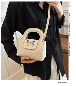 Detail of cream quilted handbag with silver bow, shown styled with a black shirt and white skirt