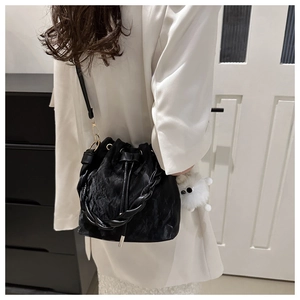 Détail du sac seau en velours noir avec poignée tressée et charm en peluche