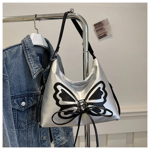 Detail of silver synthetic leather shoulder bag featuring a black butterfly and lace-up design