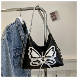 Detail of black subculture bucket bag with silver butterfly applique and bow ribbon