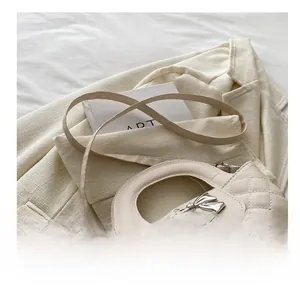 Close-up of cream quilted crossbody bag featuring a silver metal bow buckle on a blazer