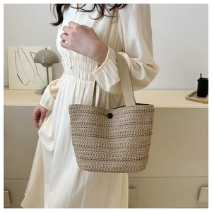Détail du sac cabas en paille tressée avec bouton noir et poignées en textile