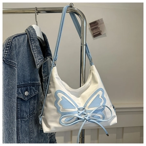 Detail of the blue butterfly patch with lace-up design on a white shoulder bag