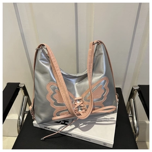 Detail of silver metallic Y2K hobo bag featuring pink butterfly patch and lace-up straps