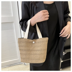 Détail de la texture tissée en paille et du bouton blanc sur ce sac à main tendance