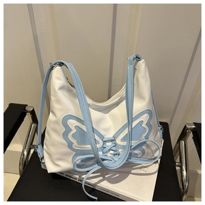 Detail of blue butterfly patchwork with lace-up accents on a white faux leather tote bag