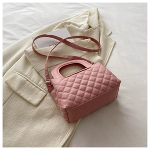 Vue détaillée du sac à main matelassé rose sur un blazer neutre très élégant