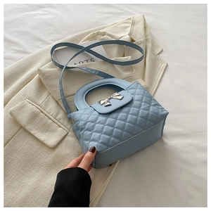 Détail d'un sac à main matelassé bleu clair avec boucle nœud argenté et anse élégante