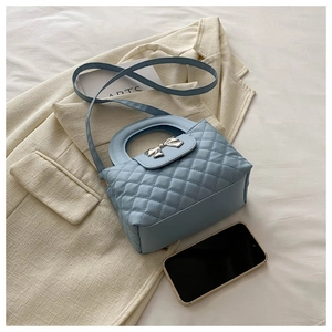 Gros plan d'un sac bleu clair matelassé avec nœud métallique et fine bandoulière