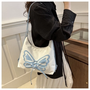 Close-up of white shoulder bag featuring light blue butterfly patches and ribbon bow details