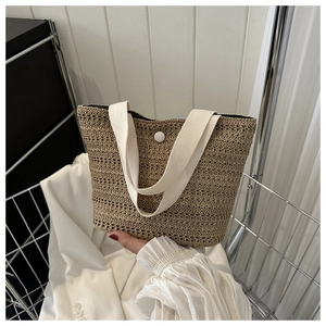 Détail du sac seau en paille avec anses en ruban crème et fermeture à bouton-pression