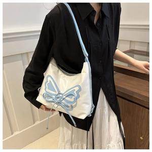 Detail of blue butterfly embroidery and bow design on creamy white shoulder bag