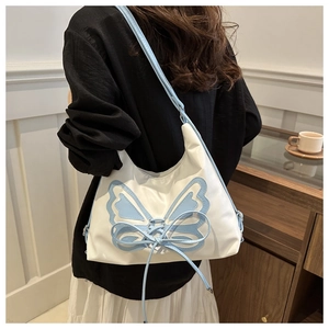Detail of white shoulder bag with blue butterfly cutout and lace-up strap design