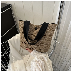 Détail du sac cabas en paille tressée avec anses en toile noire et bouton pression