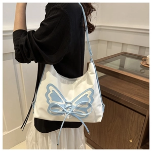 Detail of white shoulder bag featuring light blue ribbon bow and slim shoulder strap