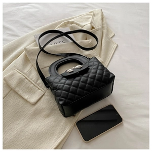 Gros plan du sac noir matelassé avec nœud argenté et téléphone pour l'échelle de taille