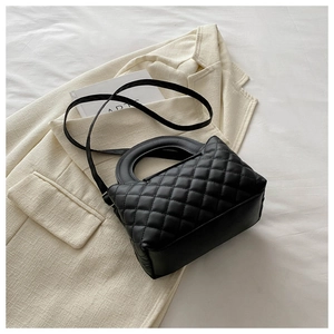 Vue de dessus d'un sac à main matelassé noir avec poignée ronde sur un blazer