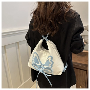 Détail du sac seau en nylon blanc avec nœuds bleus et texture en tissu satiné