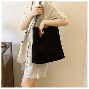 Grande borsa tote nera opaca con tracolla larga, indossata da una modella in stile minimal