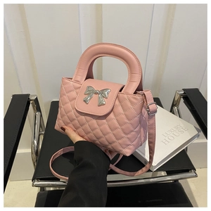 Détail d'un sac à main rose matelassé avec un nœud décoratif en métal argenté brillant