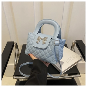 Détail d'un sac à main matelassé bleu clair avec un nœud métallique argenté décoratif