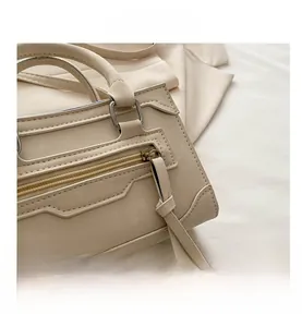 Détails de la poche zippée et des ferrures sur le sac à main en cuir beige