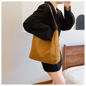 Dettaglio borsa tote in pelle scamosciata marrone con ampia tracolla spessa