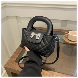 Détail du sac à main matelassé noir avec nœud argenté et poignée arrondie robuste