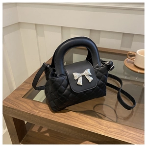 Detail of black quilted leather handbag featuring a silver metal bow buckle design