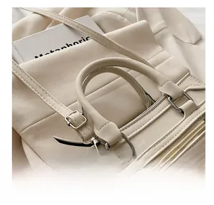 Détail du sac à main beige montrant les coutures, la mercerie argentée et l'attache