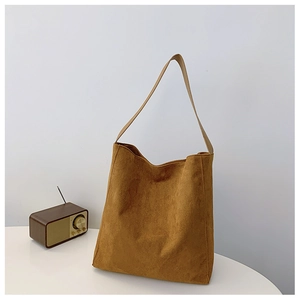 Dettaglio della borsa tote in pelle scamosciata marrone con radio vintage su un tavolo