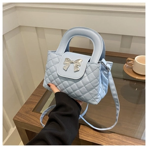 Détail du sac à main matelassé bleu clair avec nœud argenté et bandoulière réglable