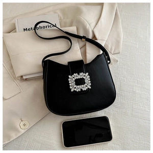 Detail of black faux leather crescent bag with a luxury sparkling crystal square buckle